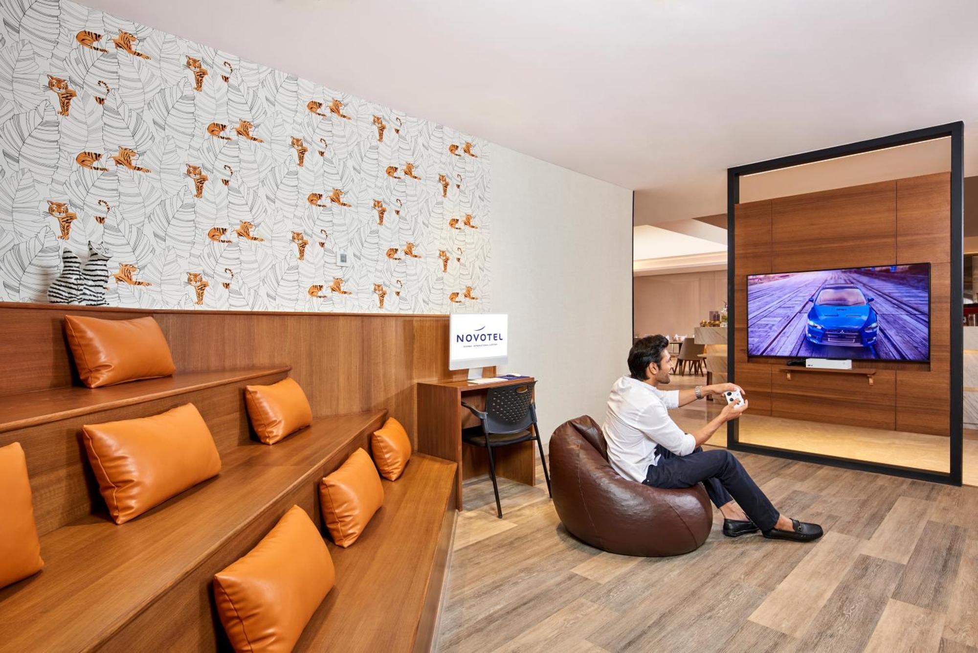Novotel Mumbai International Airport ภายนอก รูปภาพ A man playing a video game at the lounge